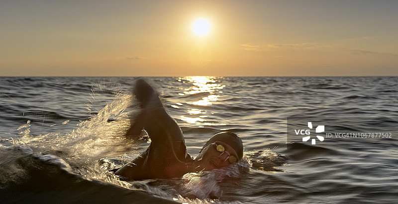 男性游泳运动员在日落前自由泳图片素材