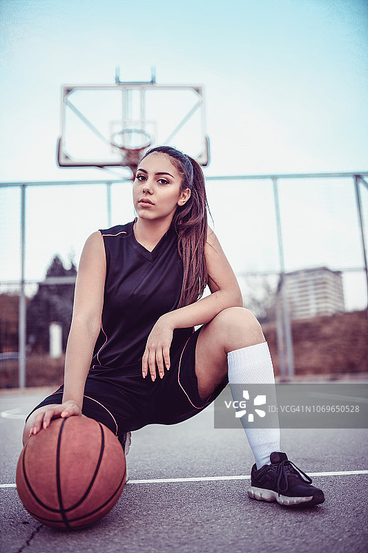 可爱的女篮球运动员摆姿势跪着图片素材