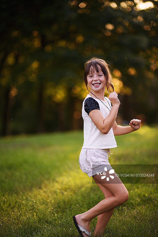 一个微笑的女孩在公园跳舞的肖像图片素材