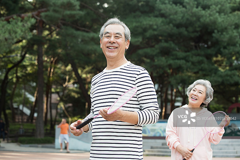 一对老夫妇在公园里笑着打羽毛球图片素材