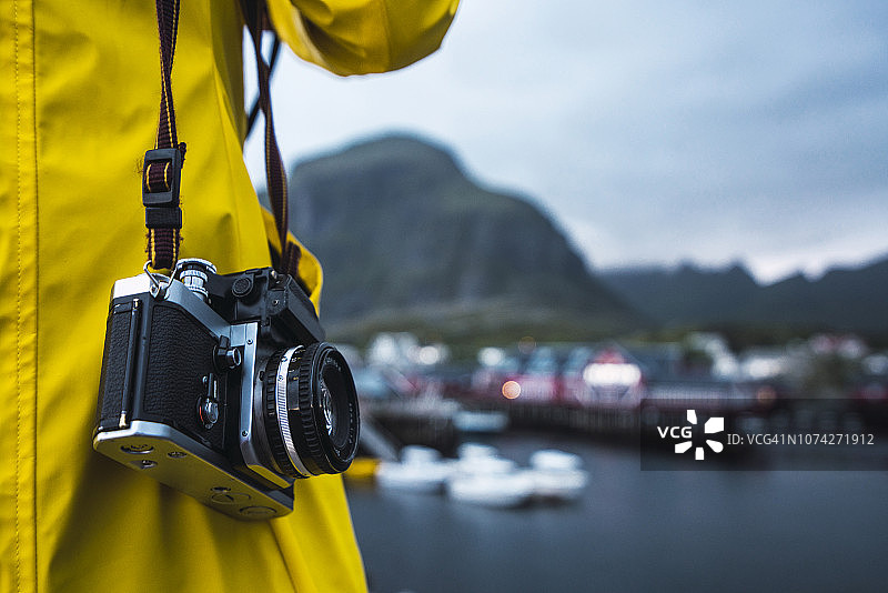 挪威罗浮敦，一名男子在一个沿海城镇拿着照相机的特写镜头图片素材
