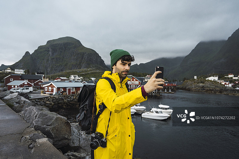 挪威罗弗敦，一名年轻男子在海边的一个渔村自拍图片素材