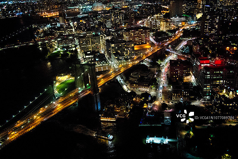 纽约布鲁克林大桥的鸟瞰图，从一架直升机在东河上方拍摄的夜晚图片素材