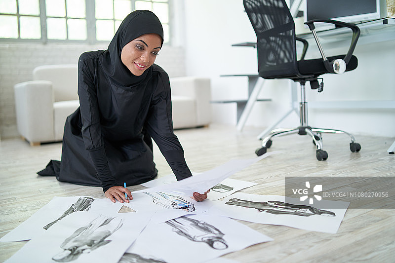 阿拉伯女设计师坐在地板上看着模特图片素材