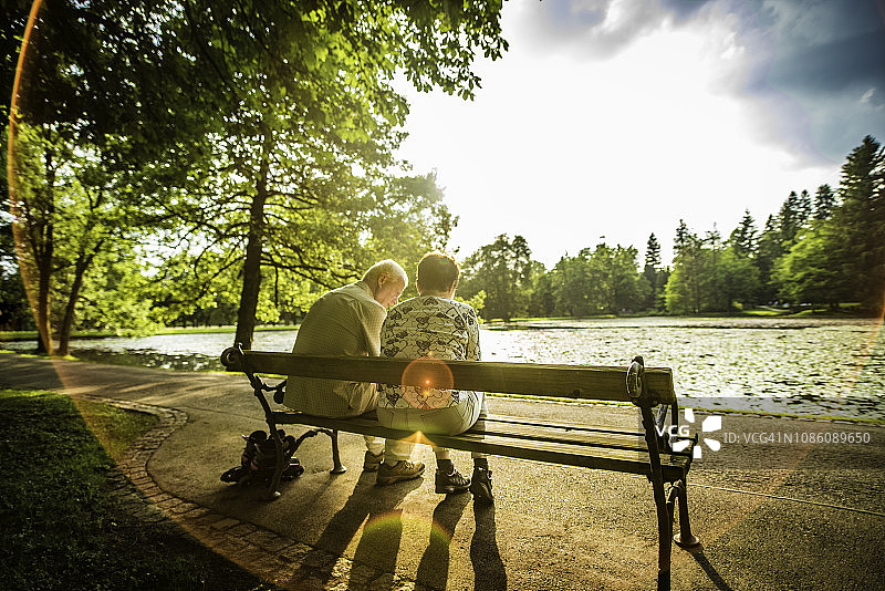 一对老年夫妇坐在公园湖边的长椅上图片素材