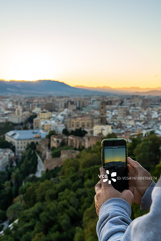 男子用手机到Málaga城拍照图片素材