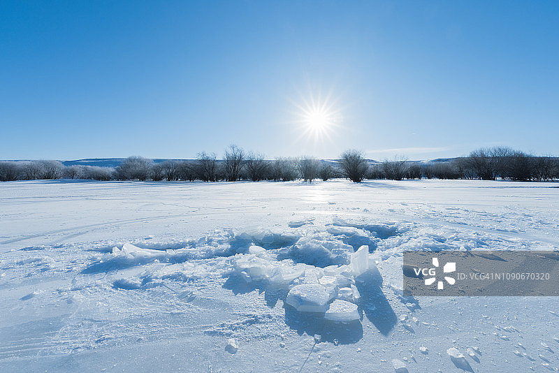在蓝天和阳光的照耀下，车辆在厚厚的冰层中穿行。图片素材