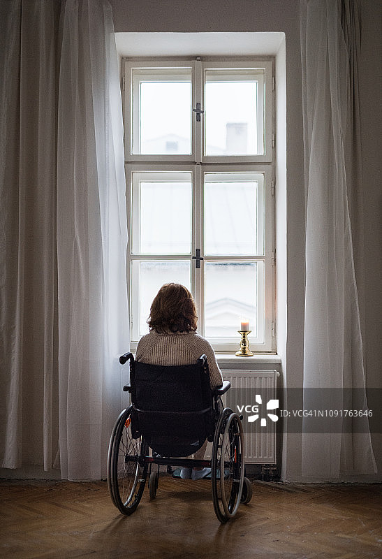 在家里坐轮椅的残疾老年妇女的后视图。副本的空间。图片素材