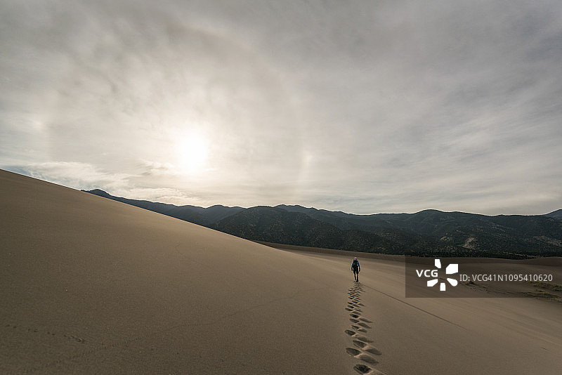 后视图徒步行走在沙漠对天空在大沙丘国家公园在日落图片素材