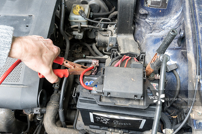 一个人用跨接线给汽车电池充电图片素材
