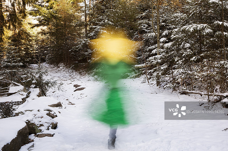 在冬天的森林里，一个穿着绿色衣服的孩子抱着一颗黄色的星星，模糊的动作图片素材