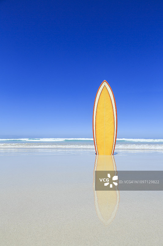 海滩上的复古黄色冲浪板。图片素材