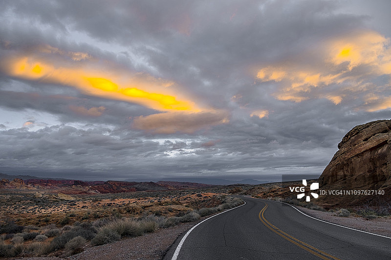 戏剧性的日出在沙漠景观与空的道路图片素材