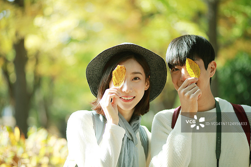年轻夫妇用树叶遮住眼睛图片素材