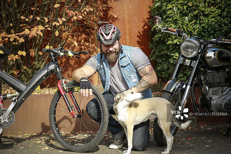 微笑的男人和狗之间的摩托车和自行车图片素材