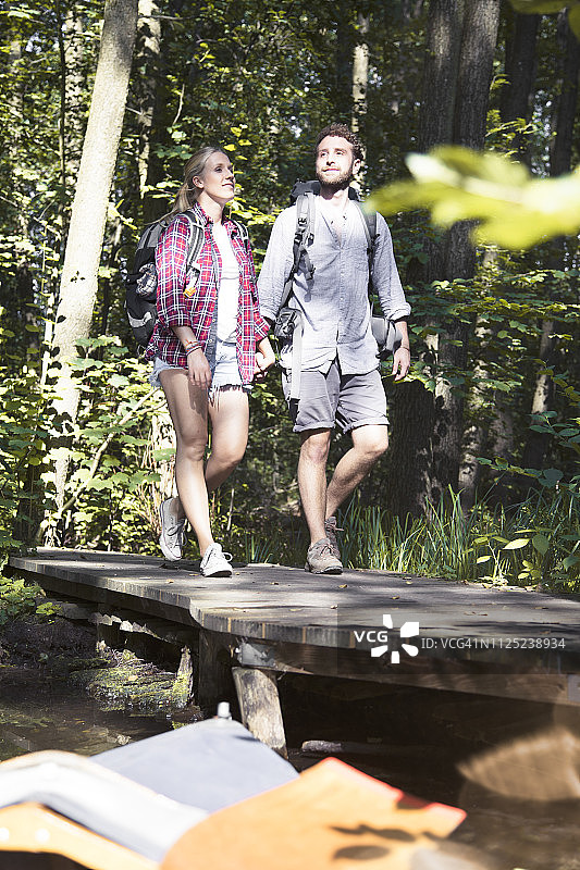 一对年轻夫妇在森林里穿过一座桥图片素材