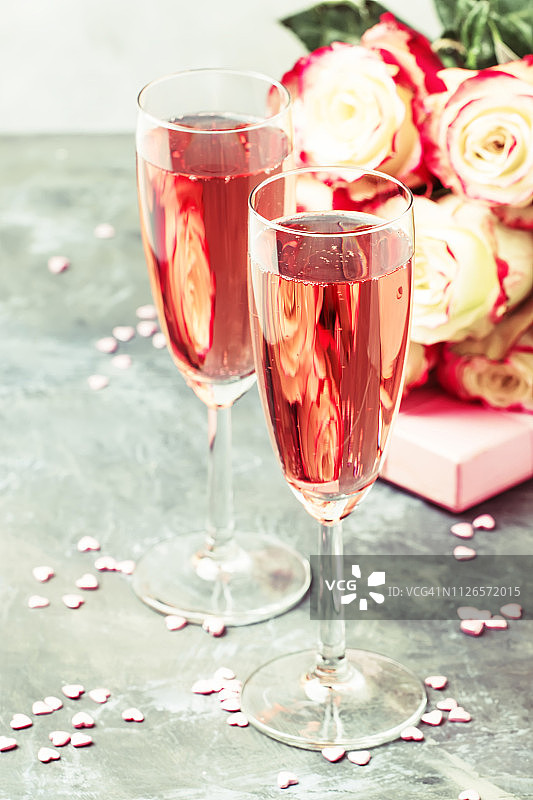 爱的象征-白玫瑰和红玫瑰的花束，礼品盒，粉色或玫瑰香槟或起泡酒的玻璃杯图片素材