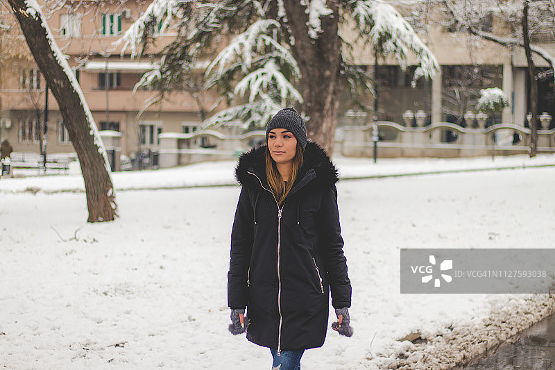 迷人的女人走在白雪覆盖的公园里图片素材