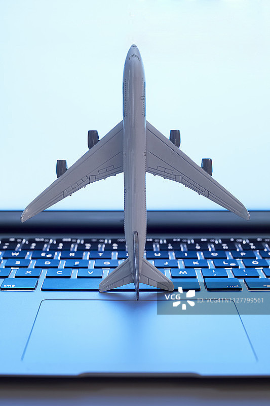 笔记本电脑上的一架小飞机的静物，旅行和在线预订的象征图片素材
