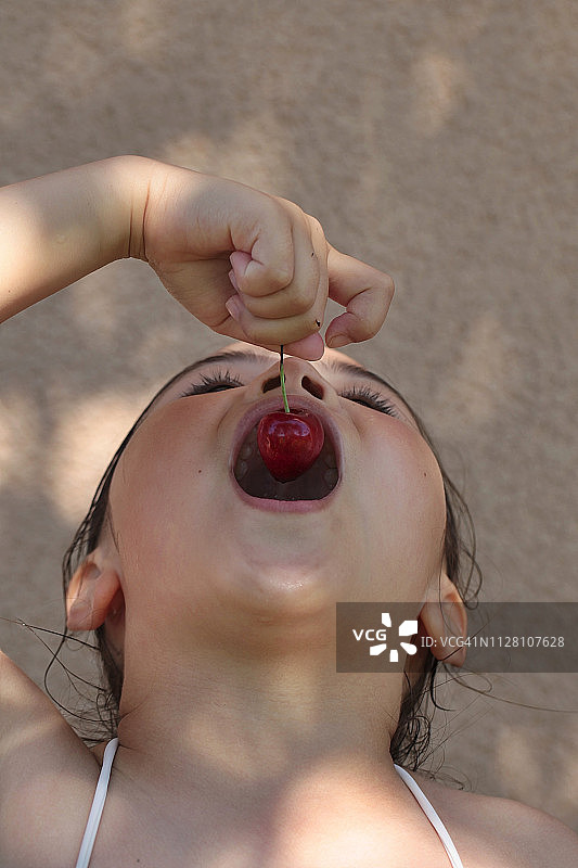 一个女孩在夏天吃樱桃的特写。图片素材