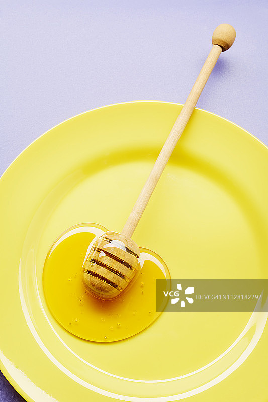 黄色盘子上的蜂蜜和蜂蜜勺的静物图片素材