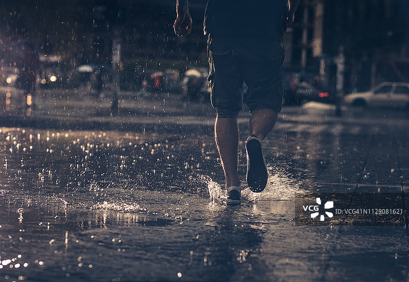 一个不认识的人在雨中奔跑的背影。图片素材