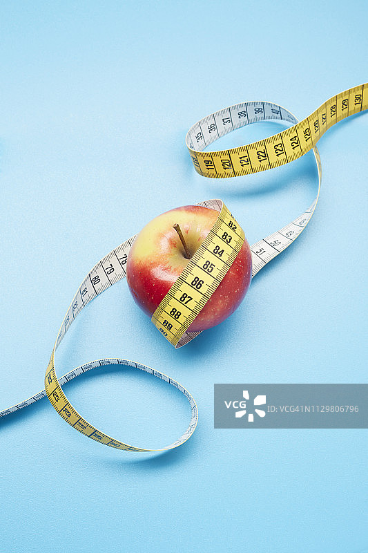 高角度的苹果和卷尺上的蓝色背景图片素材