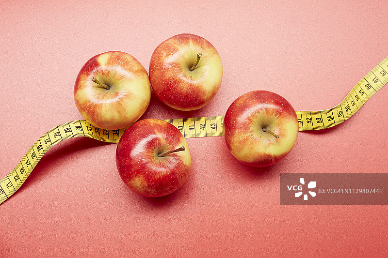 高角度的苹果和卷尺上的红色背景图片素材