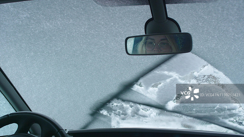 司机的观点。汽车刮擦窗户上的雪图片素材