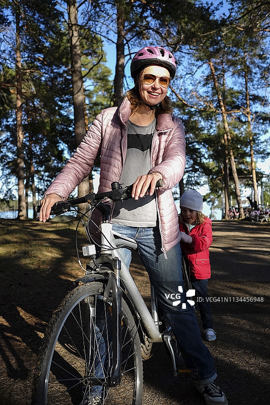芬兰，库奥皮奥，母亲和女儿骑着自行车在森林小径上图片素材