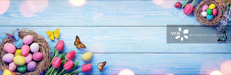 复活节-蓝色木板上的郁金香和带蛋的巢图片素材