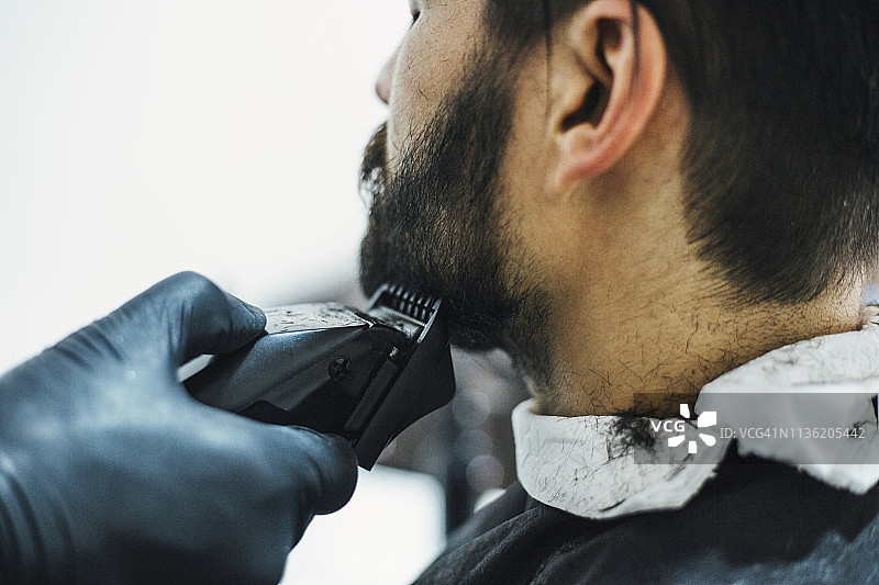 一个男人正在用电动剃须刀修剪他的胡子图片素材