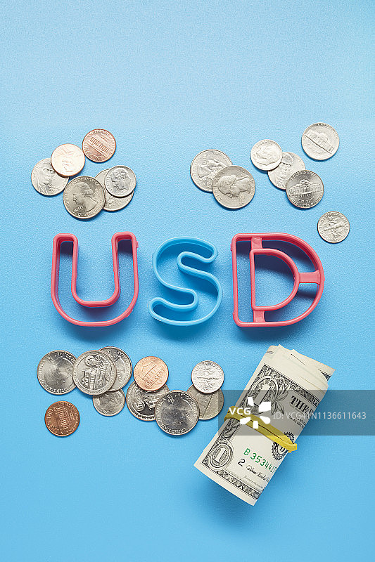 在蓝色背景上的美元信件和一卷美元钞票的静物生活图片素材