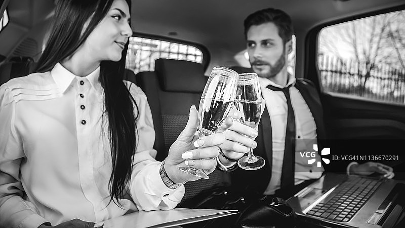 商务人士在长途商务旅行后在车里喝香槟图片素材