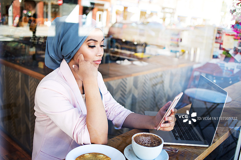 年轻的穆斯林妇女在咖啡馆工作图片素材