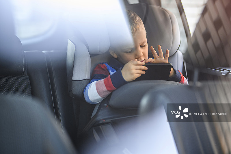 一个小男孩在汽车安全座椅上使用手机图片素材