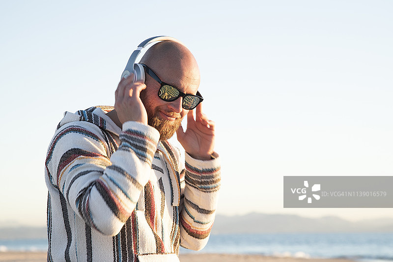 海滩上戴着耳机和太阳镜的男人图片素材