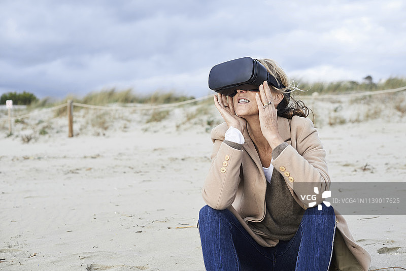 西班牙，Menorca，资深女性在冬天的海滩上使用VR眼镜图片素材