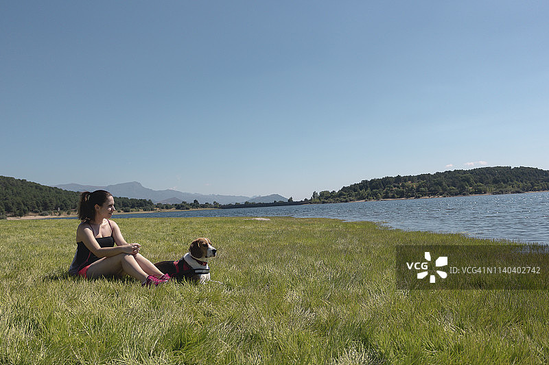 一个年轻女人和她的狗在湖边图片素材