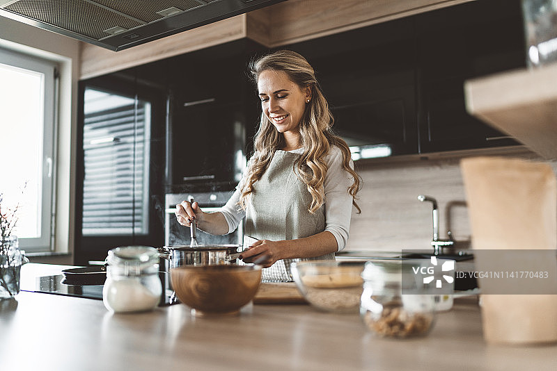 一个金发女人在现代化的厨房里做饭图片素材