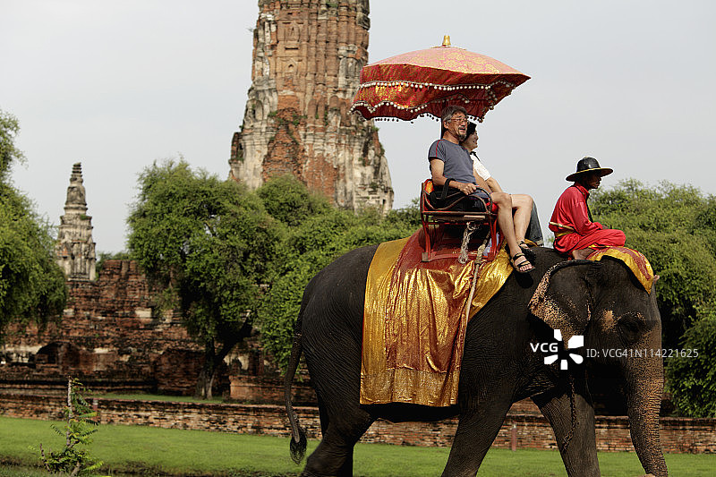 游客骑着大象在泰国大城府的石窟前图片素材