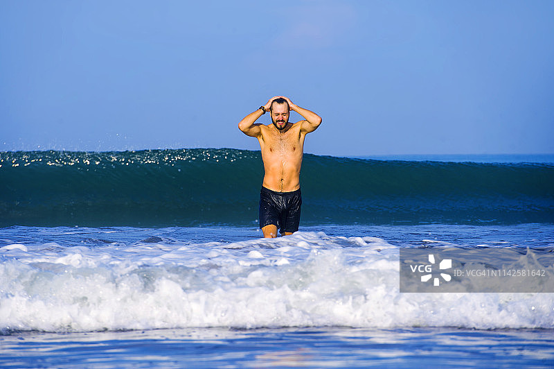 年轻有吸引力和快乐的男人胡子和泳裤在热带天堂沙漠海滩独自嬉戏和愉快的海水享受夏季假期目的地孤立的蓝色图片素材