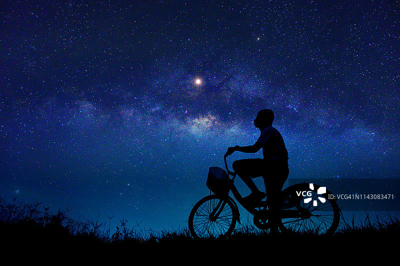 这个男孩在银河系中骑自行车图片素材