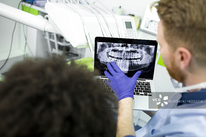 牙医在笔记本电脑上向病人展示全景牙科x光图像图片素材