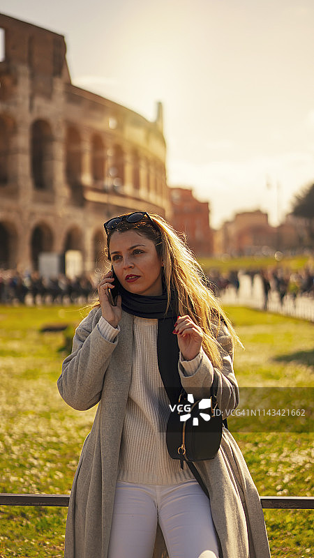 一个金发女人在罗马圆形大剧场前打电话图片素材
