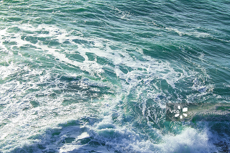 风景:阳光照耀着海面，海浪拍打着海岸图片素材
