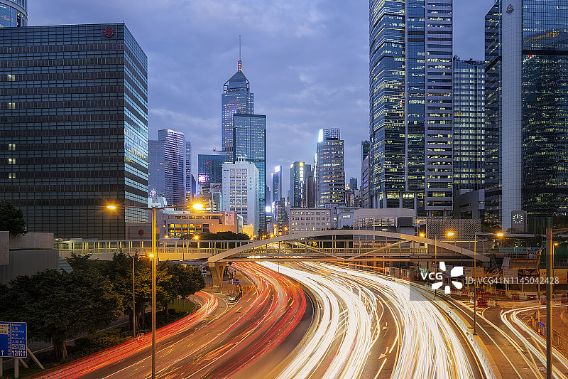 长时间暴露在城市的灯光下，夜间交通的运动模糊了香港的现代摩天大楼图片素材