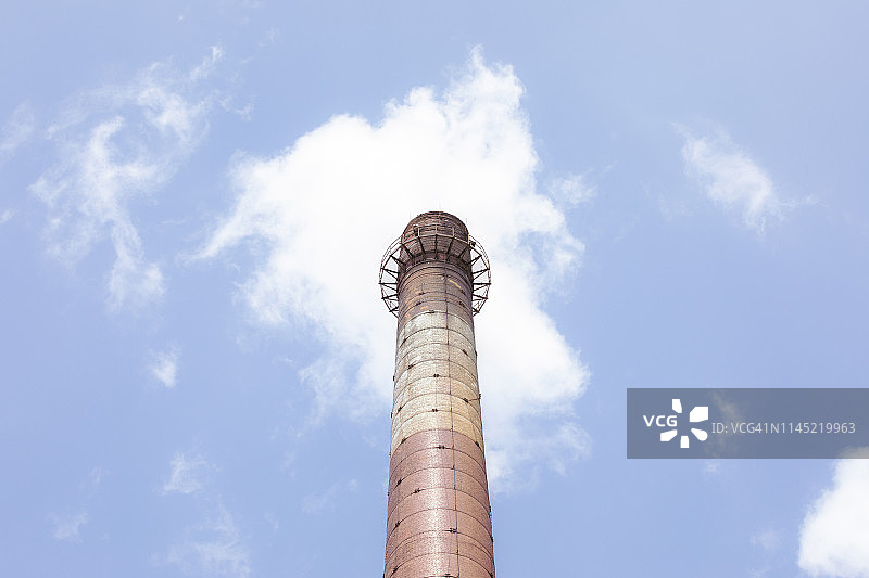 能源革命。高砖工业烟囱顶在阳光下。背景有小云和蓝天。红色和白色的。旧工业建筑。西里西亚,波兰。关闭了。煤炭工业。图片素材