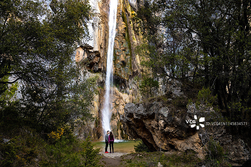 一对相爱的夫妇在加泰罗尼亚比利牛斯山一个荒凉而宁静的地方发现了美丽的高瀑布。图片素材