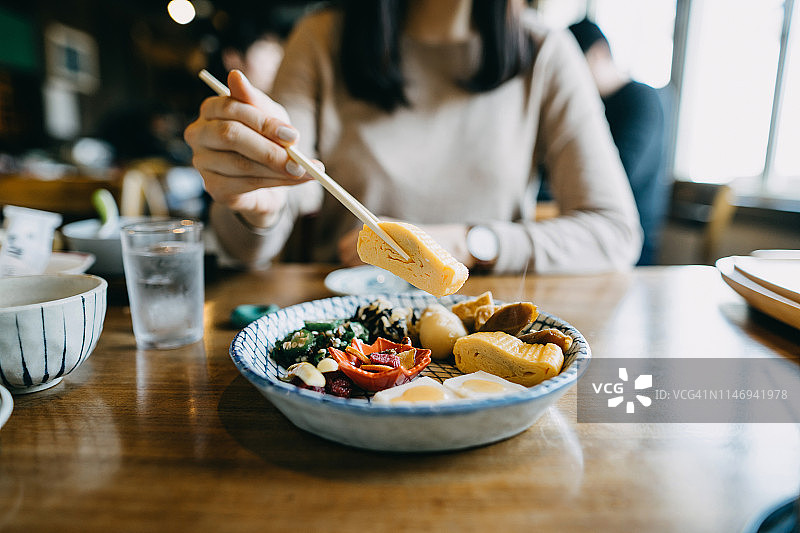 近距离拍摄的年轻女子享受精致的日本料理在餐厅图片素材